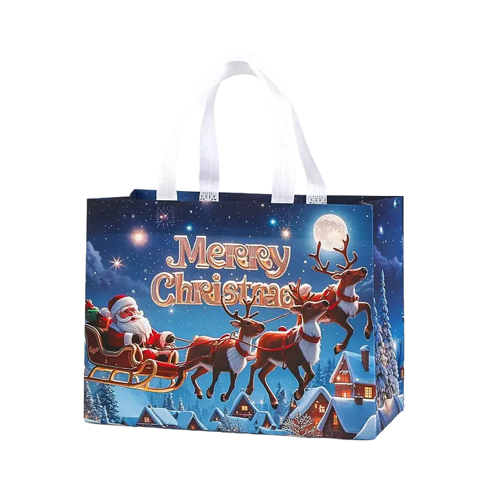 Blue Christmas tote bag with white handles featuring Santa Claus riding a sleigh with reindeer over a snowy Christmas village under a starry night sky