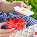 Clear food storage container with white lid and yellow centre seal holding watermelon